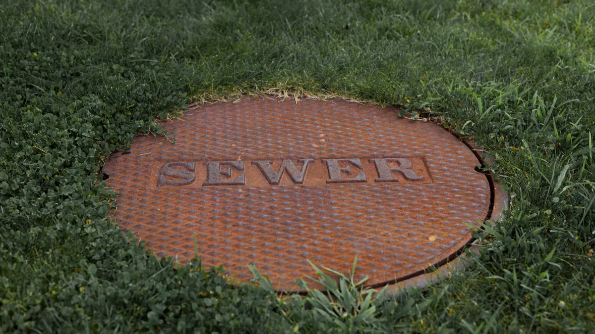Drain and Sewer Solutions — The Complete Guide manhole cover labeled sewer in grass