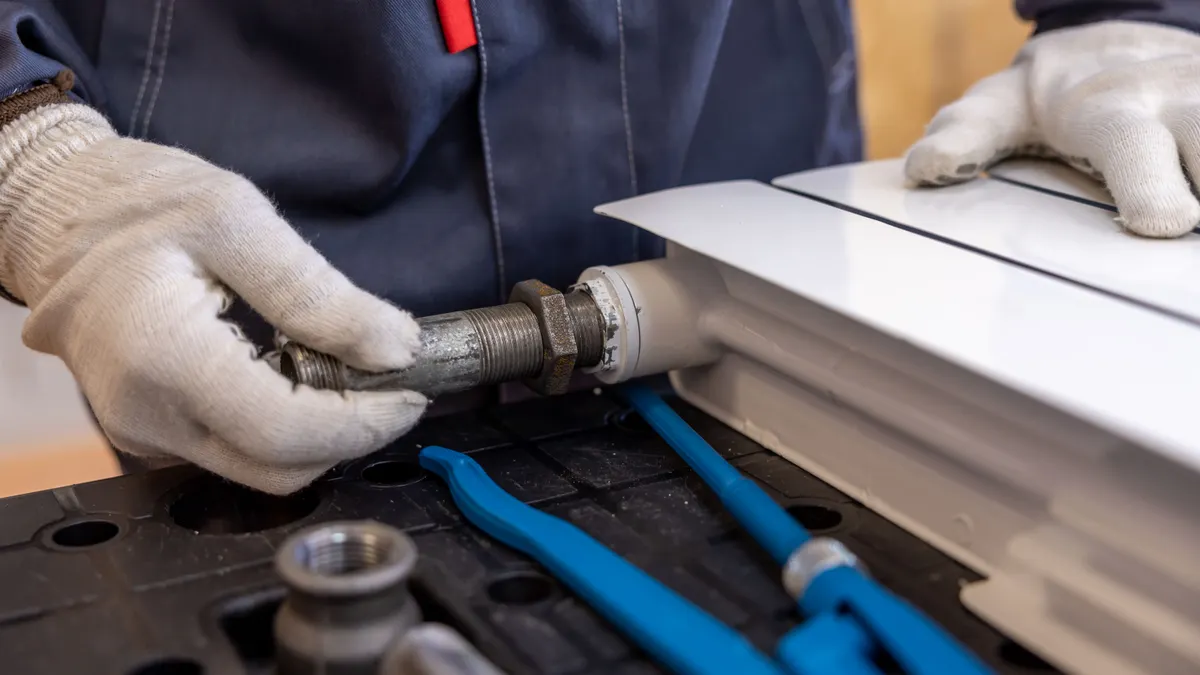 Gloved plumber working on metal pipe fittings